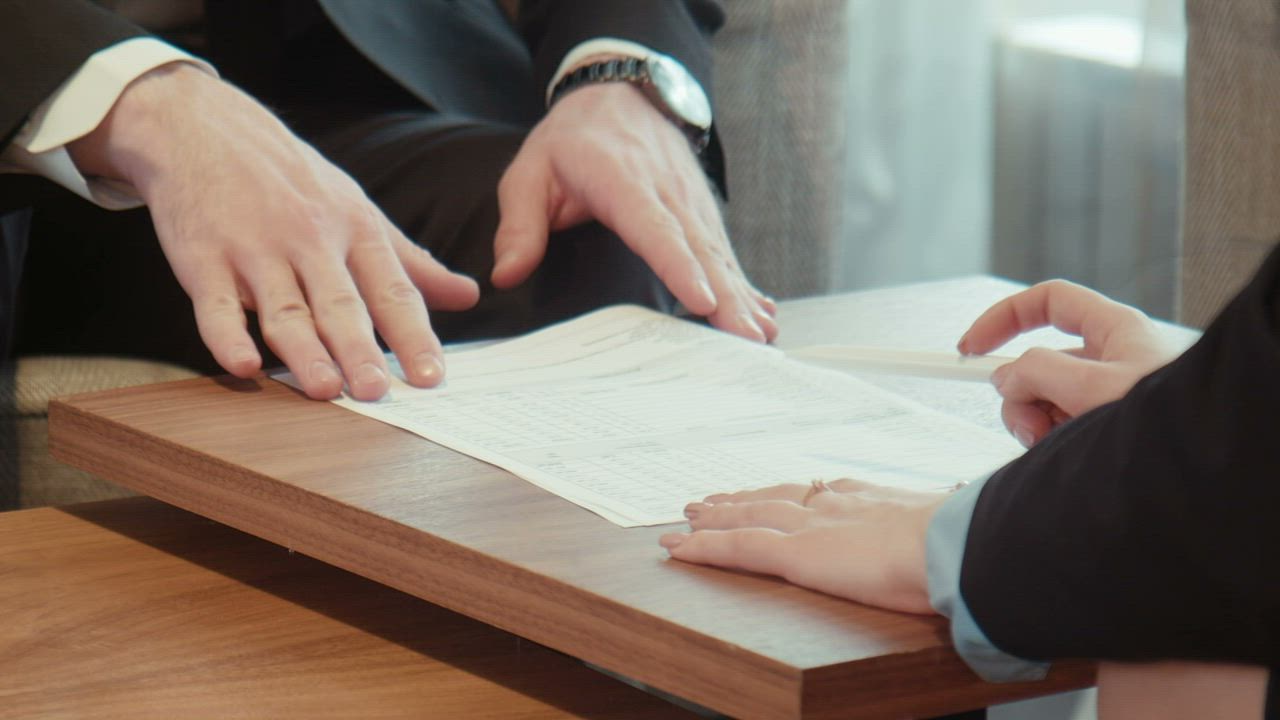 couple signing videography contract at wooden table