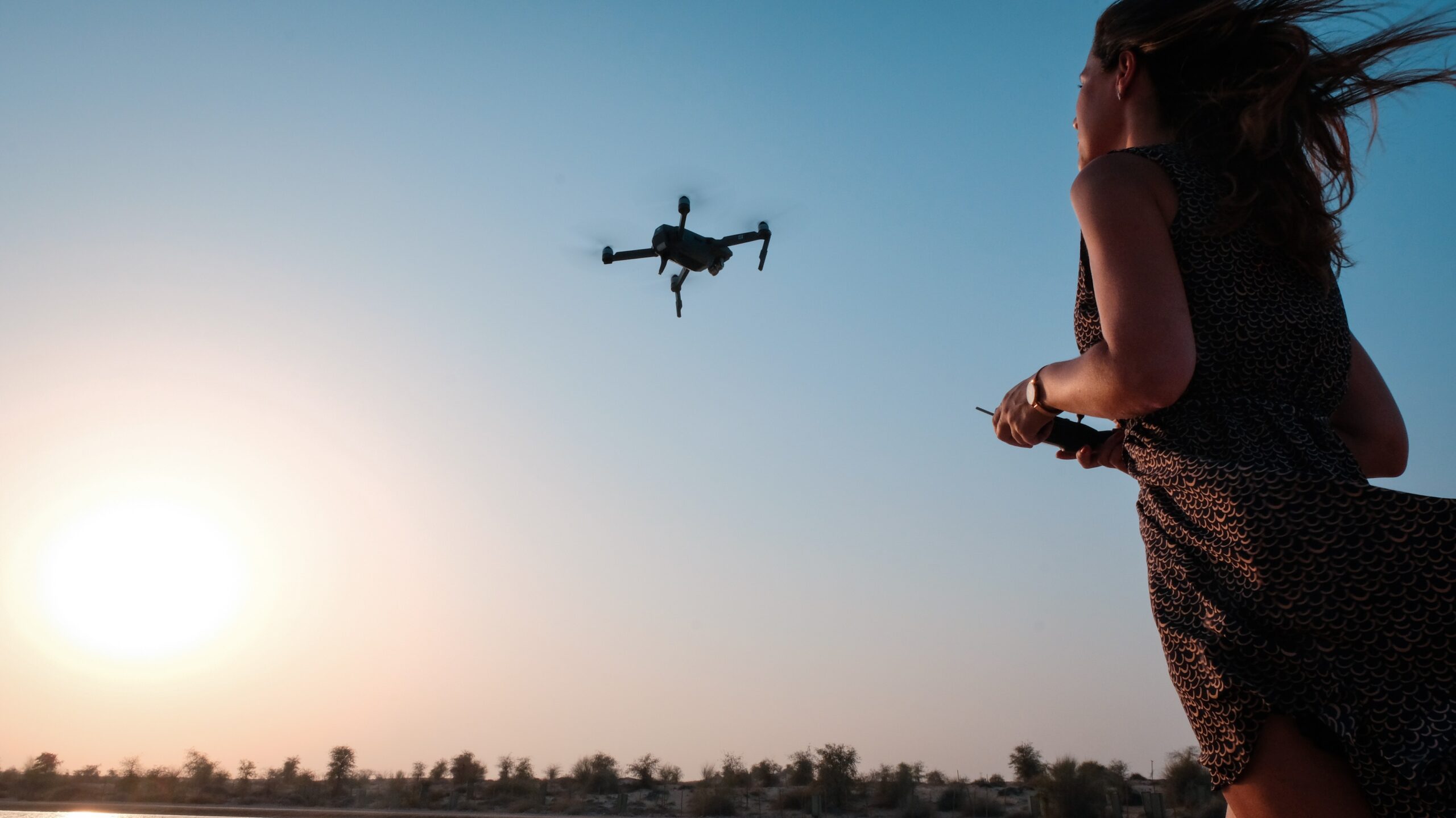 drone operator flying drone outdoors at golden hour
