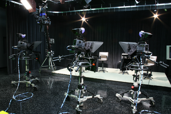 two camera operators setting up tripods at a gala event