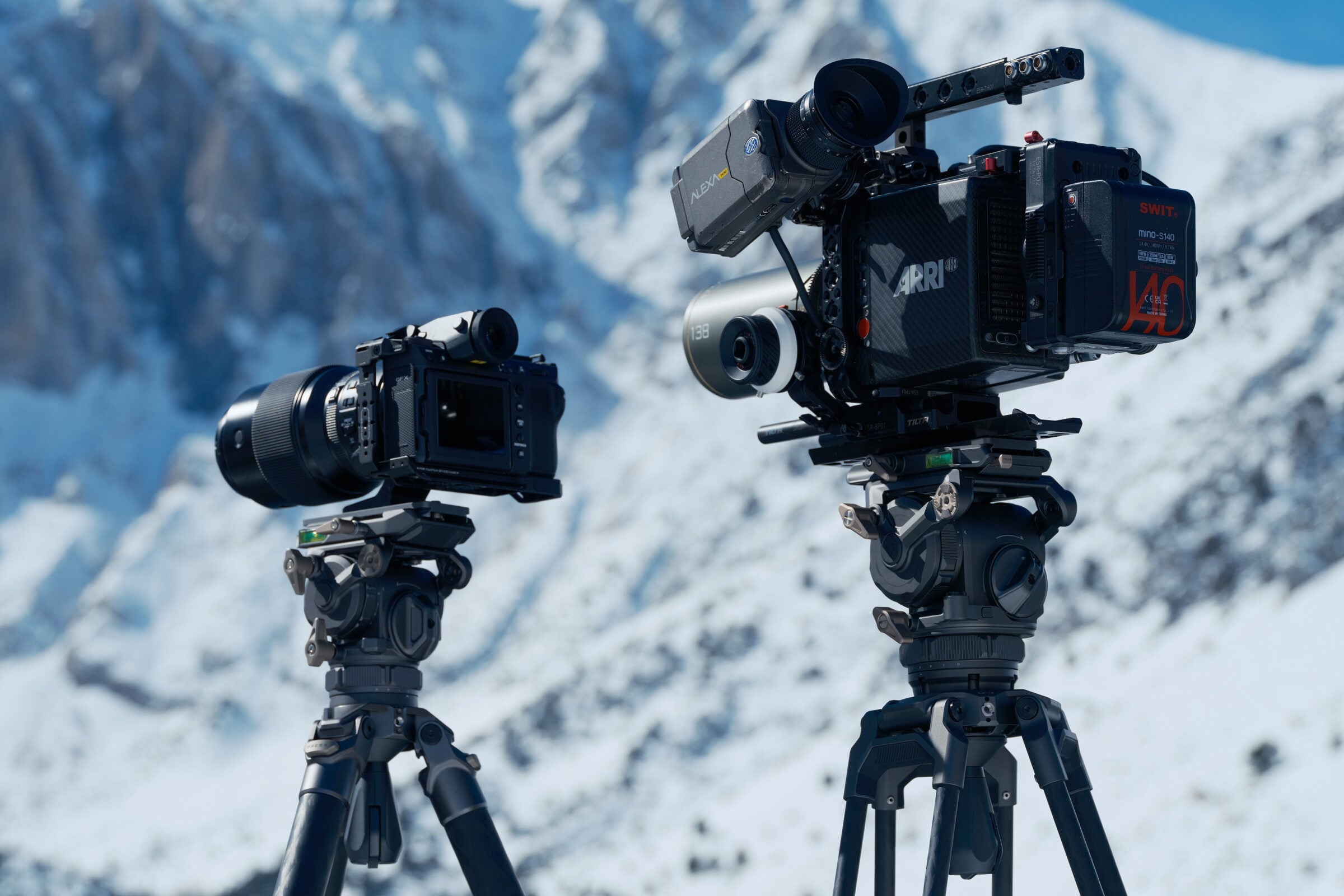 videographer mounting camera on fluid-head tripod outdoors