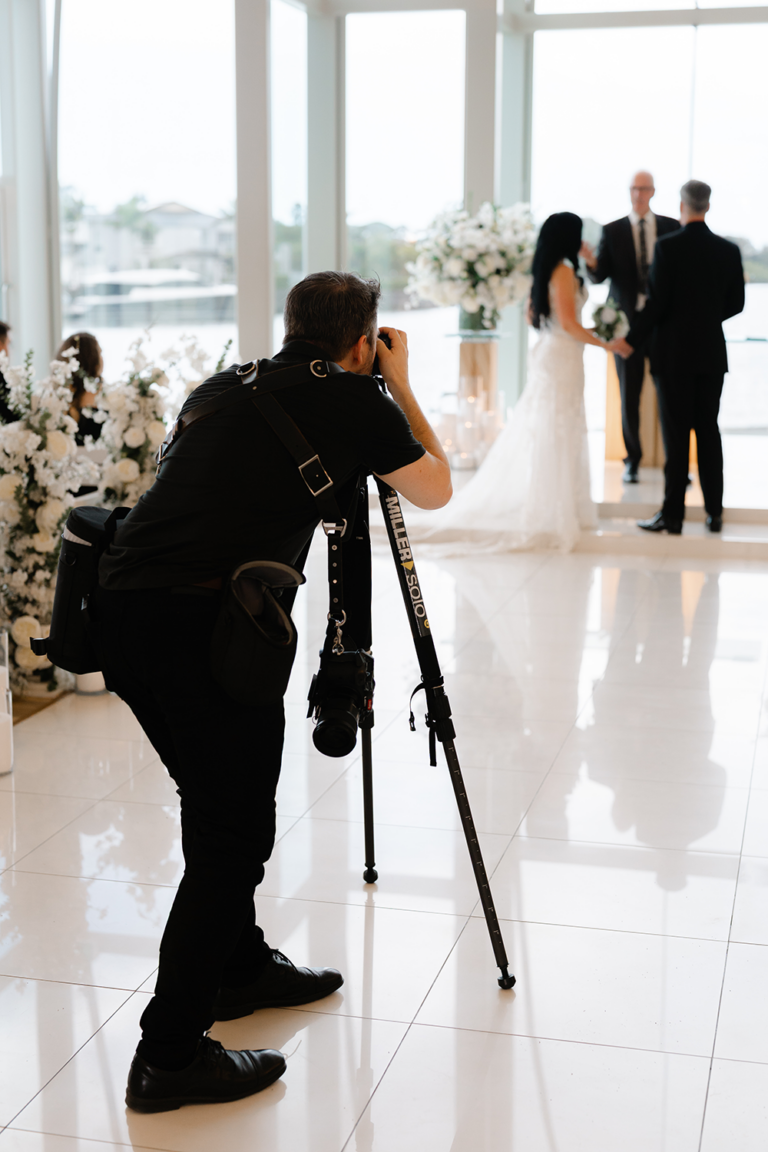 videographer setting up tripod in wedding venue ballroom