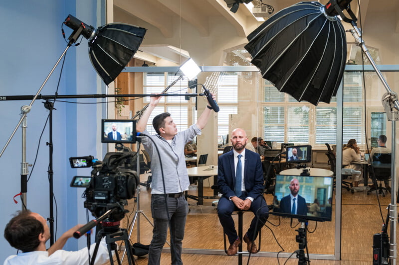 videographer adjusting camera lighting for office interview